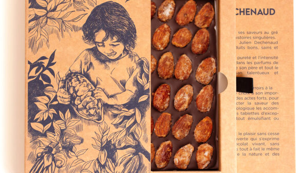 Tablette de chocolat noir et amandes caramélisées du chef Julien Dechenaud chocolatier à Paris et Vincennes. La tablette est dans son étui illustré de fève de cacao
