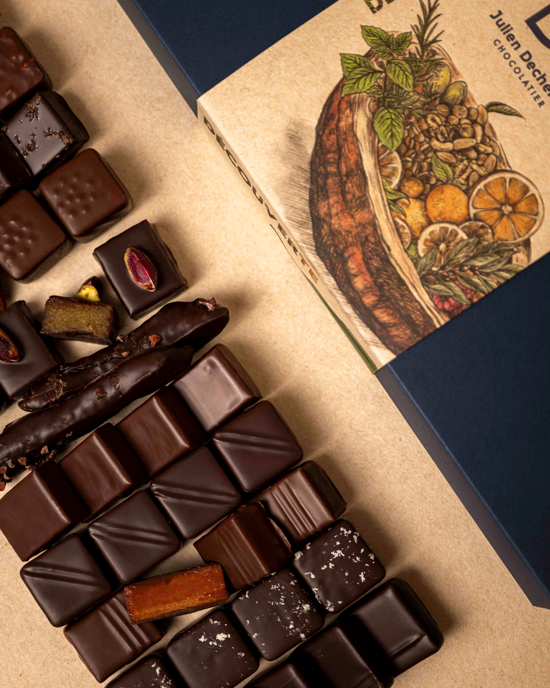 Crop sur la boite découverte de 67 chocolats : ganaches pures origines, ganaches parfumées, pralinés, citronettes, orangettes et gingembrettes composent cet assortiment, un coffret signé Julien Dechenaud chocolatier torréfacteur à Paris.
