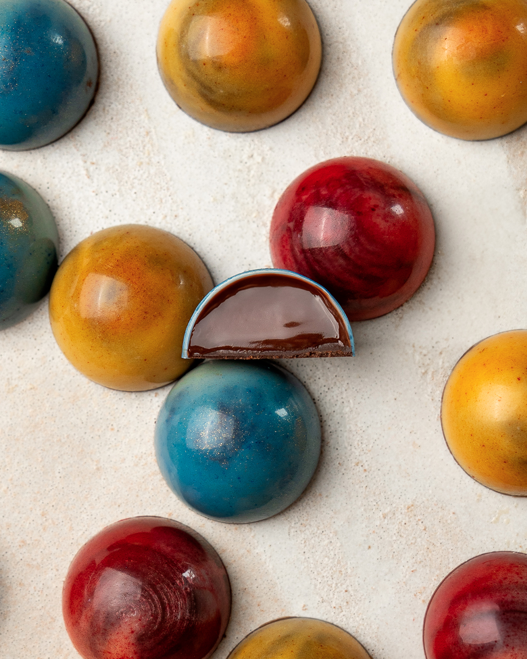 Demi-sphères pour noël. Neptune : caramel citron vert | Mercure :  caramel orange | Jupiter : caramel pamplemousse. Des créations de la collection de noël 2025 par Julien Dechenaud chocolatier à Paris et Vincennes.