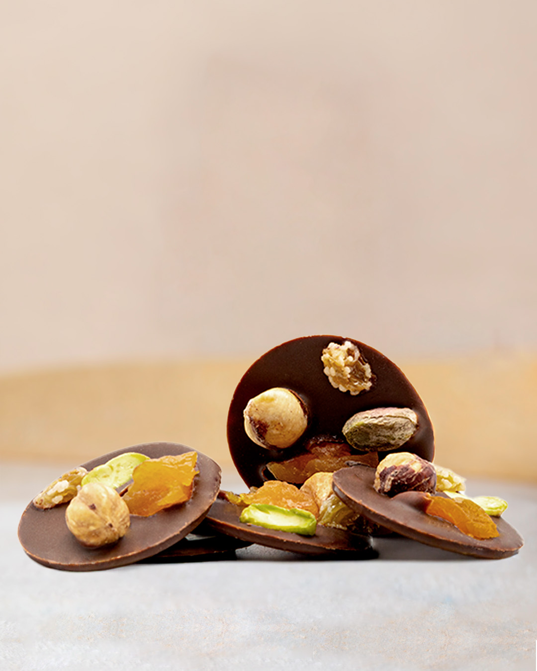 Sachet de mendiants au chocolat au lait. Palets de chocolat noir è0% Cameroun et noisettes, pistaches et fruits secs.