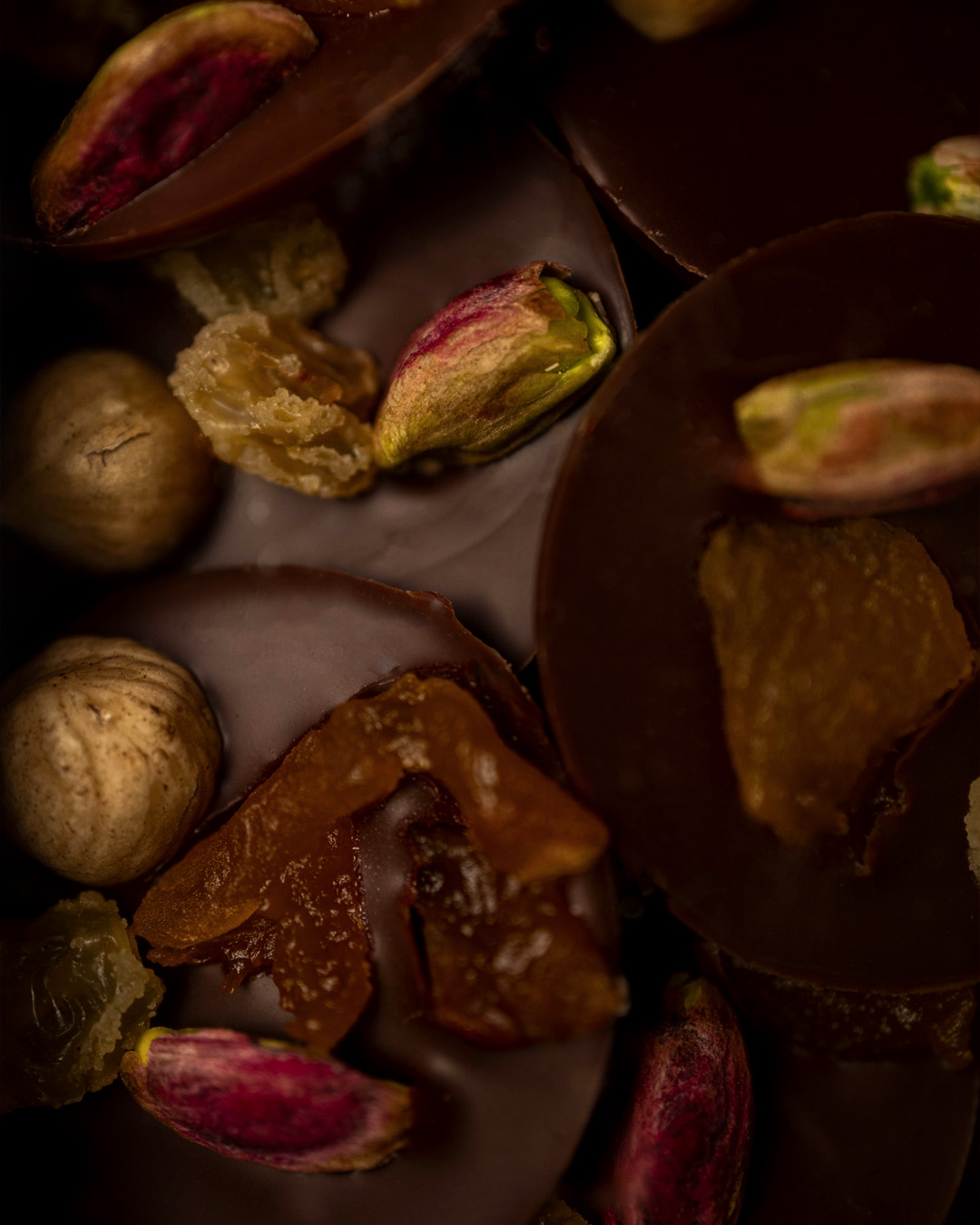 Palets de chocolat noir 70% Cameroun, recouverts de noisettes pistaches et fruits secs.